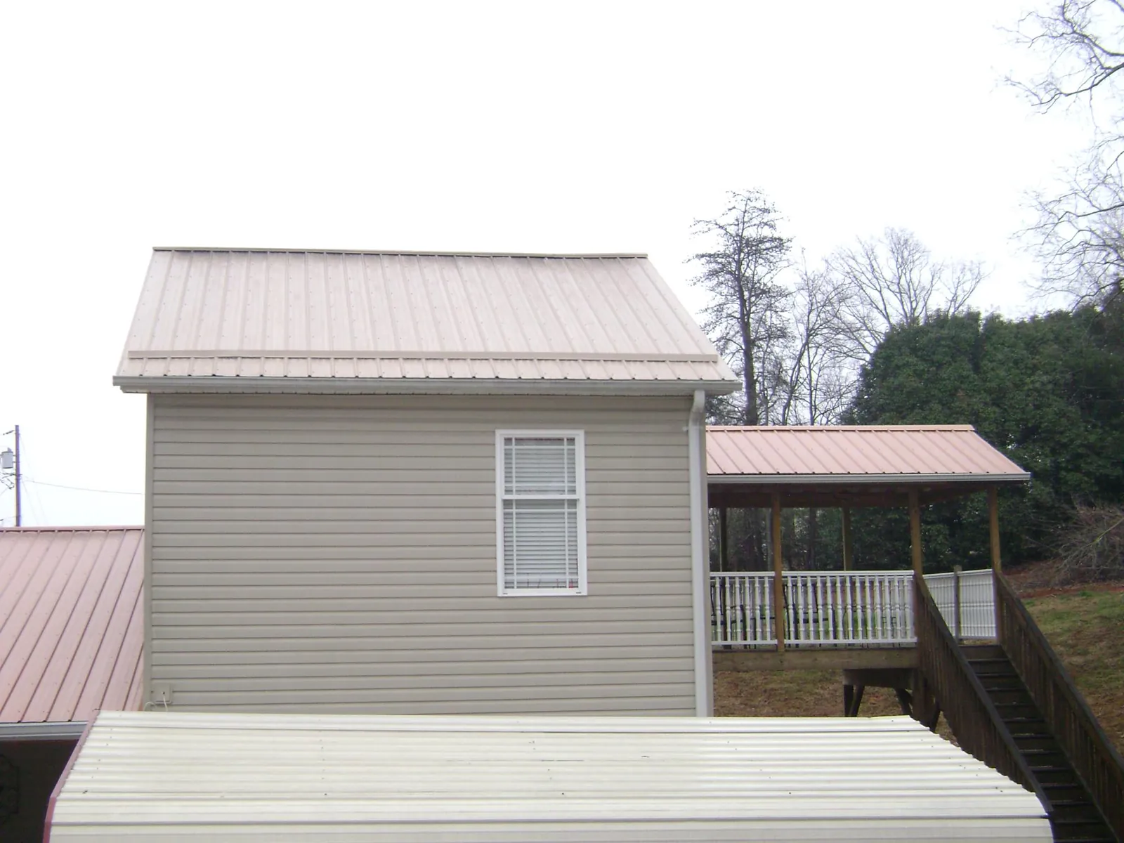 Tan metal roofs on a two story addition and attached porch, from a Roof Replacement job in Bucyrus